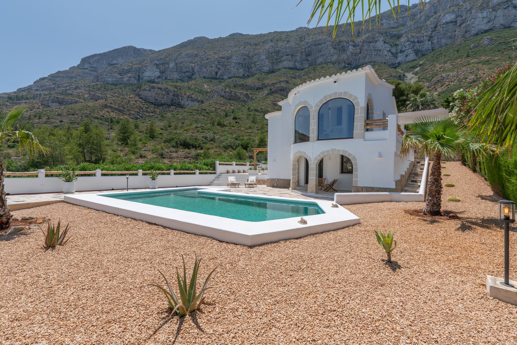 Wit huis met zwembad aan de voet van de Montgó bij Dénia, met agaves en palmen op de voorgrond