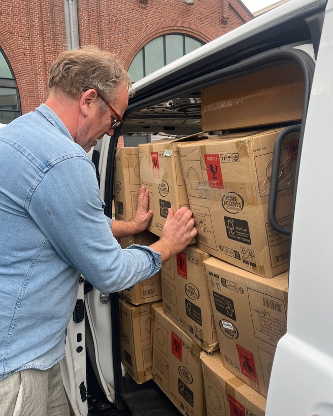 Dennis schuift dozen op hun plek in een bestelbus die tot het dak is volgeladen